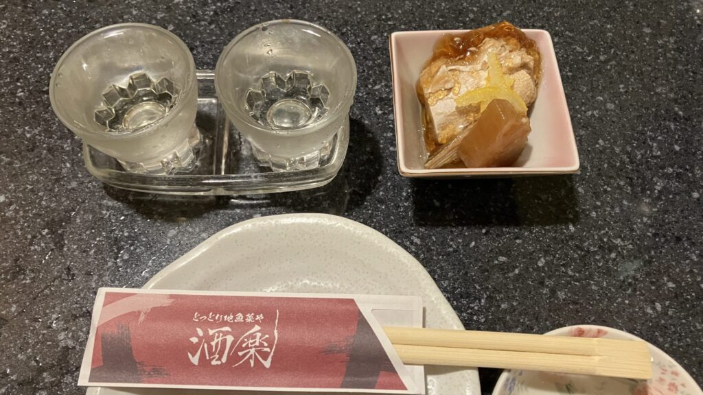 酒楽の日本酒飲み比べセットとお通しのブリ大根の画像
